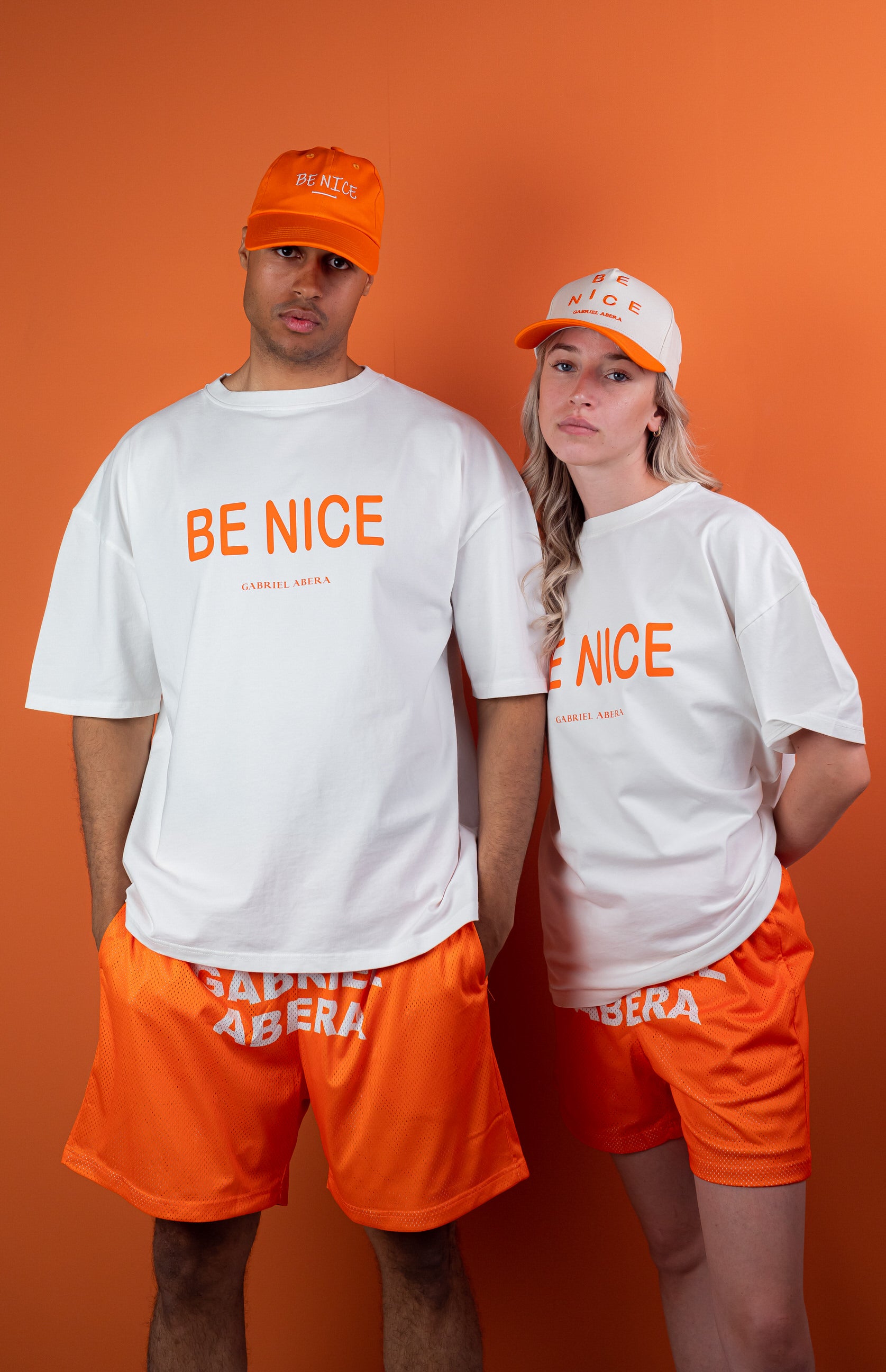 Male and female model wearing an Orange mesh shorts with white brand name print in the front