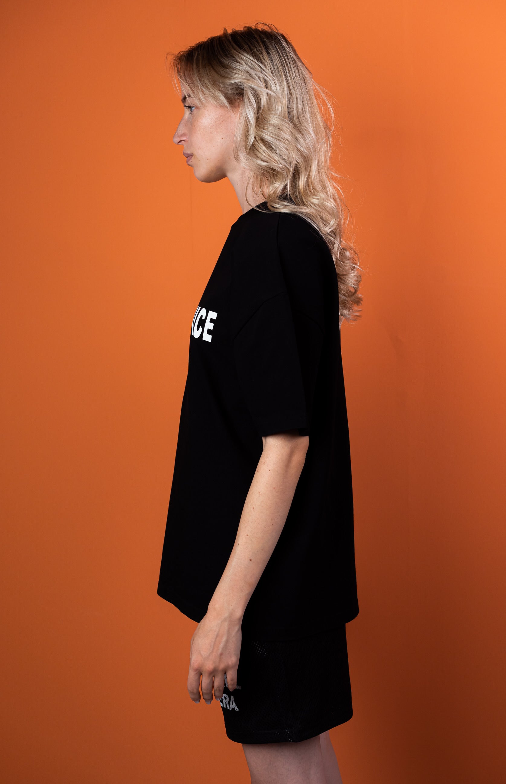 Female model wearing a Black oversize tshirt with white talk to me nice design on the front