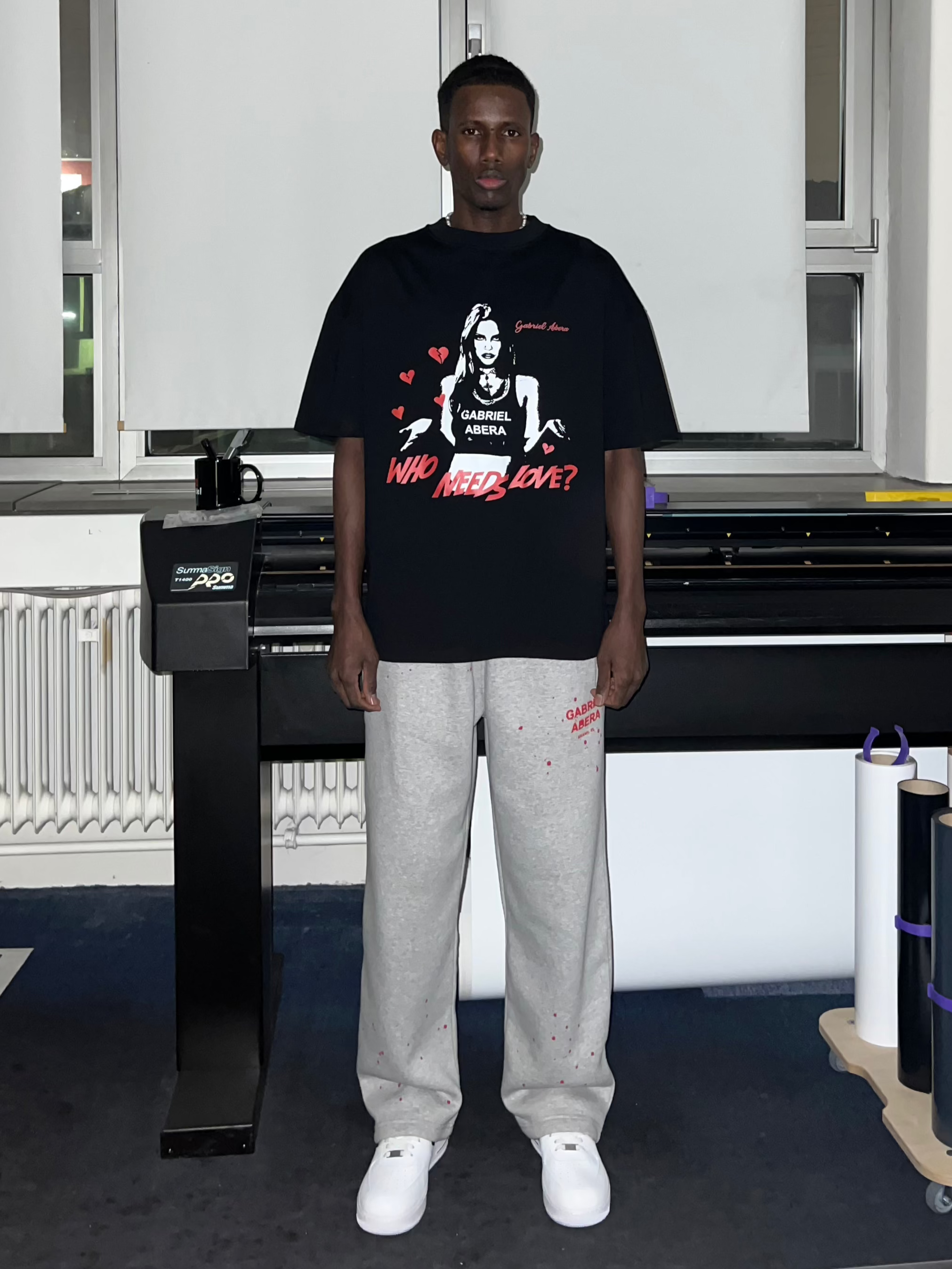 Front view of Black Rebel Heart T-Shirt featuring bold woman print, 'Who Needs Love?' message, and urban streetwear style."