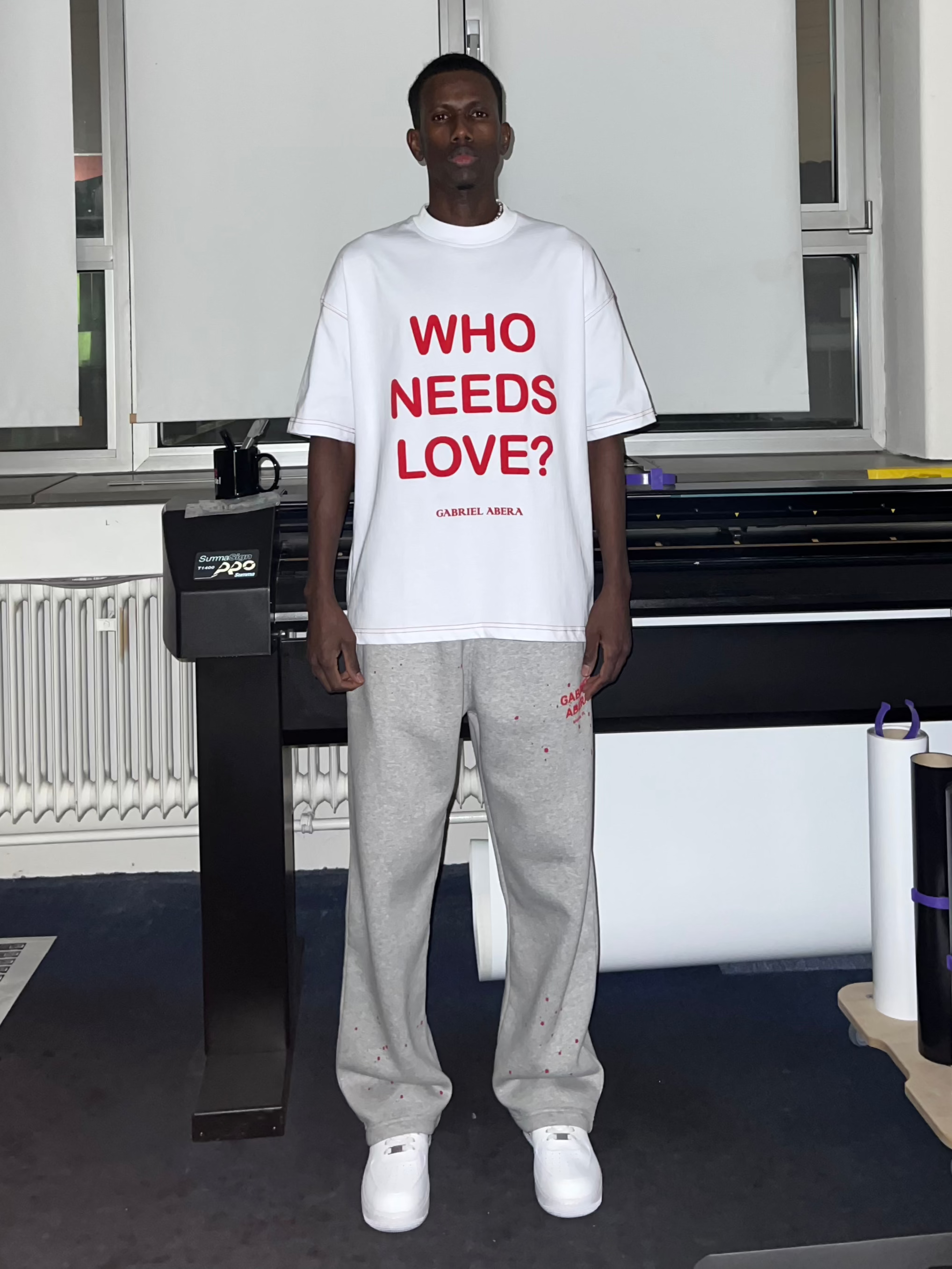 Front view of Grey 'Who Needs Love?' Puff T-Shirt with bold puff print, red seam detail, and oversized streetwear fit.