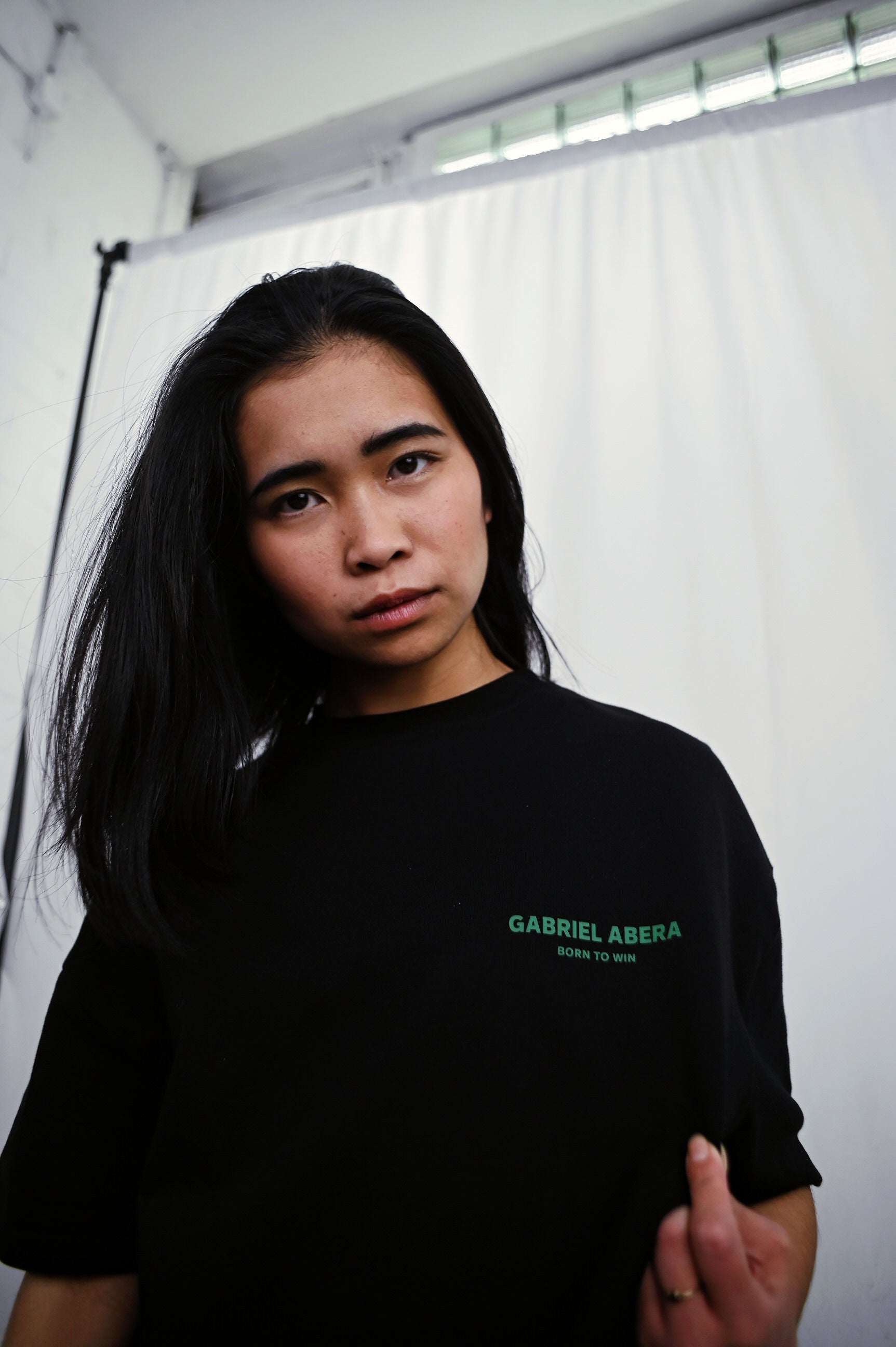 Female model wearing a Black oversize tshirt with green born to win design on the back