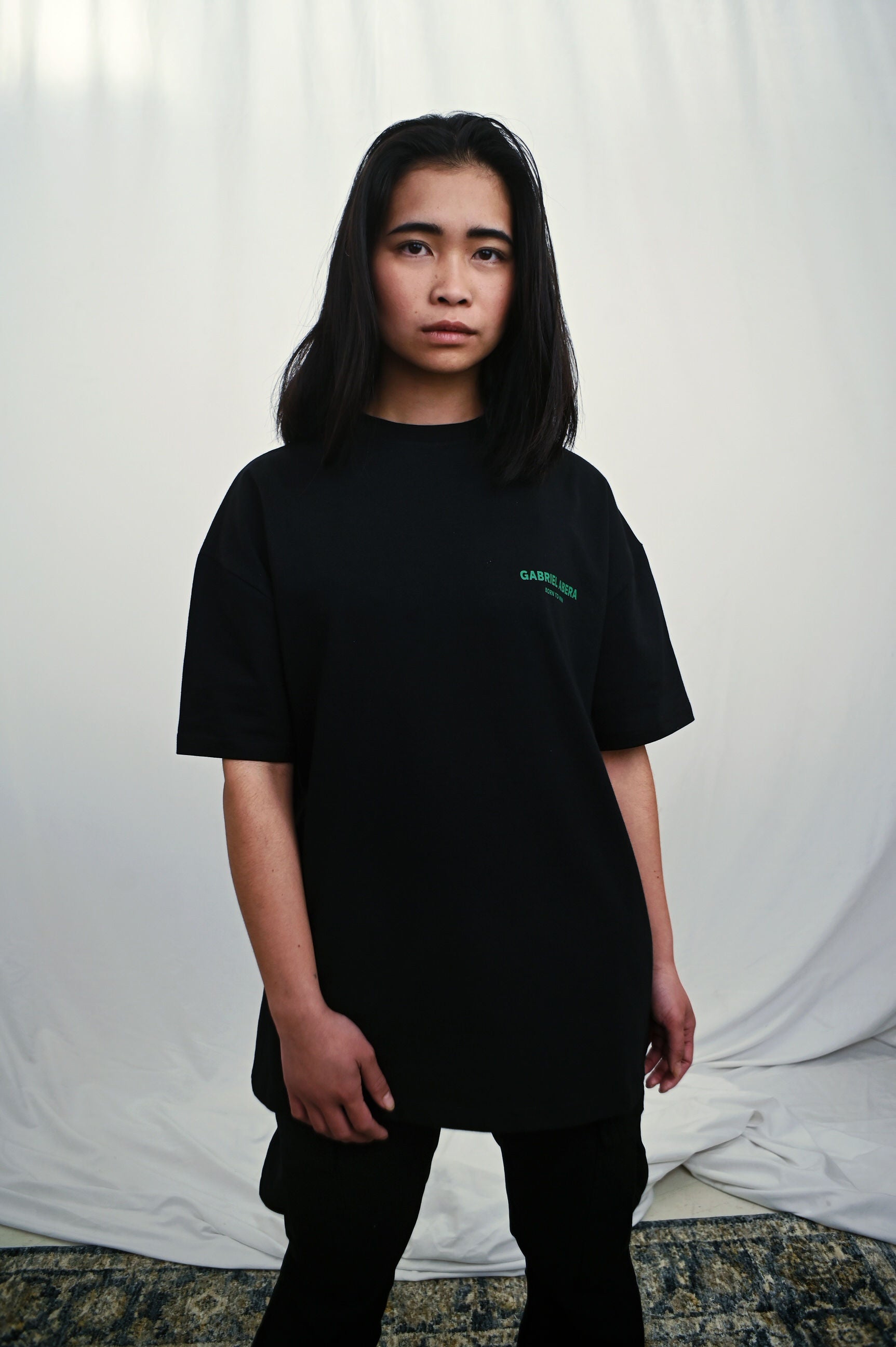 Female model wearing a Black oversize tshirt with green brand design on the front